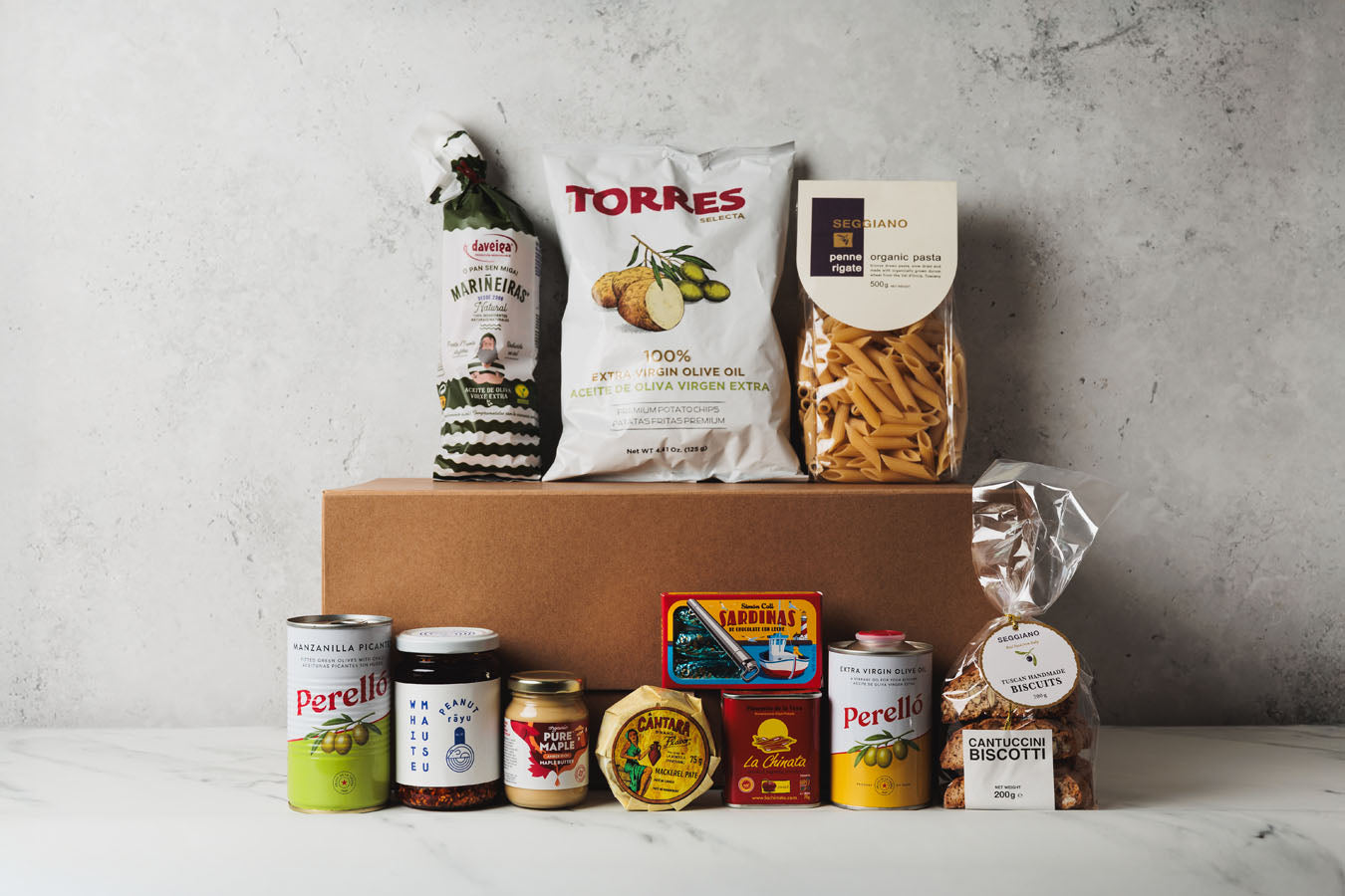 Collection of food items including a box, bottles, and packaged goods on a gray surface.